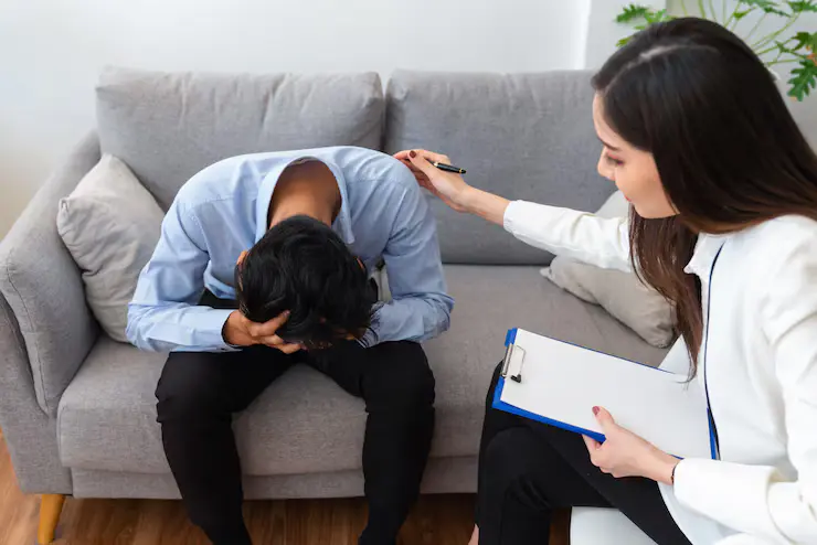 https://thedrpsycho.com/wp-content/uploads/2025/05/stressed-asian-young-man-patient-have-life-problem-sitting-sofa-with-hands-holding-his-head-while-woman-psychiatrist-trying-console-him_34755-474.webp
